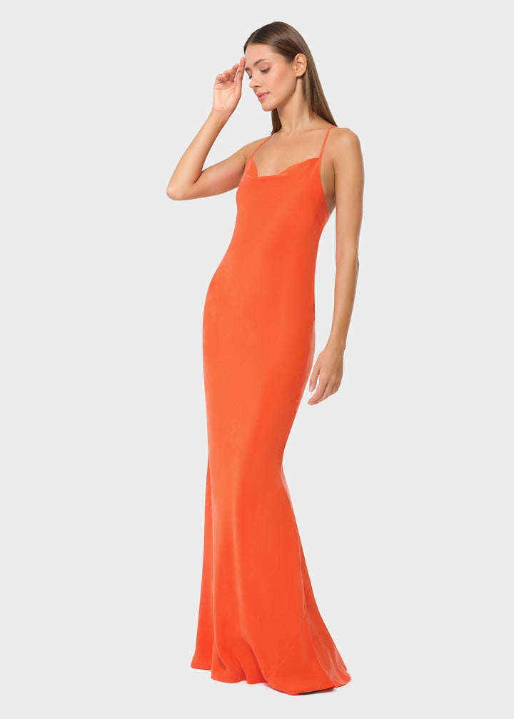 Woman wearing bright orange vegan silk slip maxi dress, side profile view