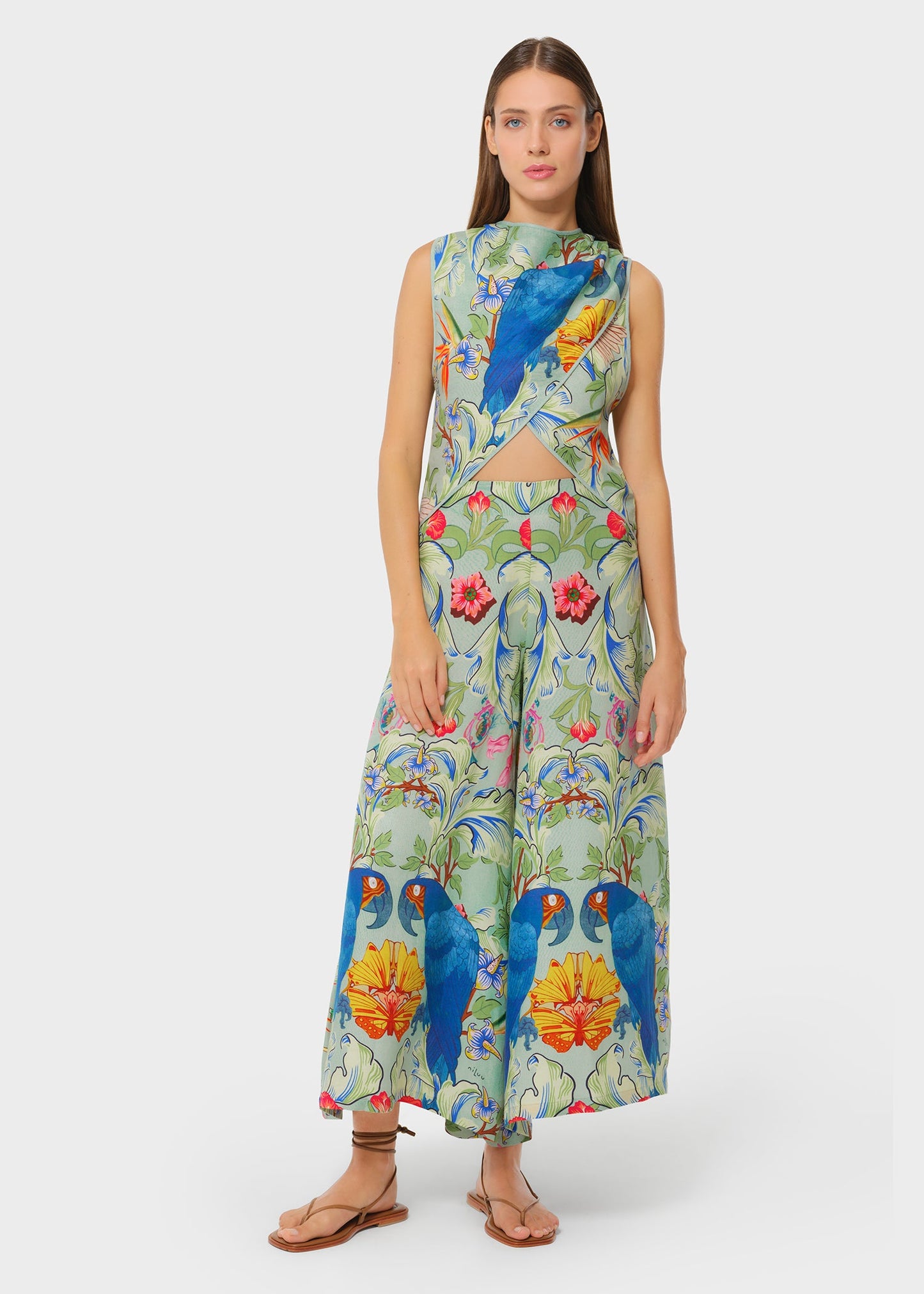 Full-length front view of the printed co-ord set with vibrant florals and blue parrots. Sleeveless crossover top with a subtle waist cutout, paired with flowing wide-leg pants.