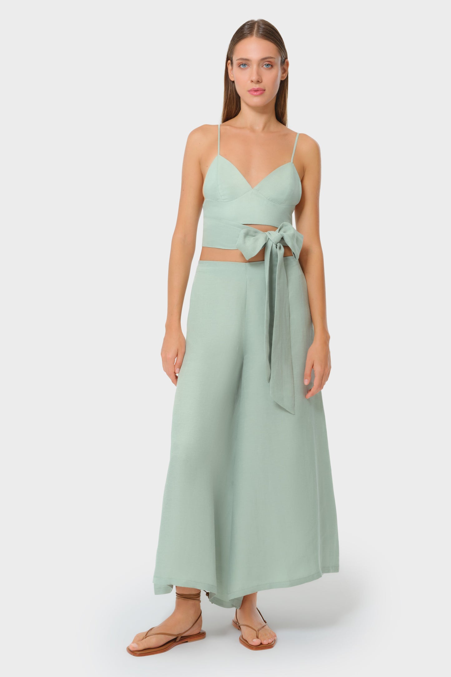 Woman wearing a luxury mint green vegan silk bralette top and matching bow-tie maxi skirt, resort wear