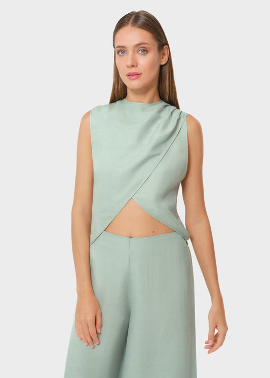 Woman wearing a mint green sleeveless wrap crop top with a high neckline and matching wide-leg pants, resort-style set against a neutral background.