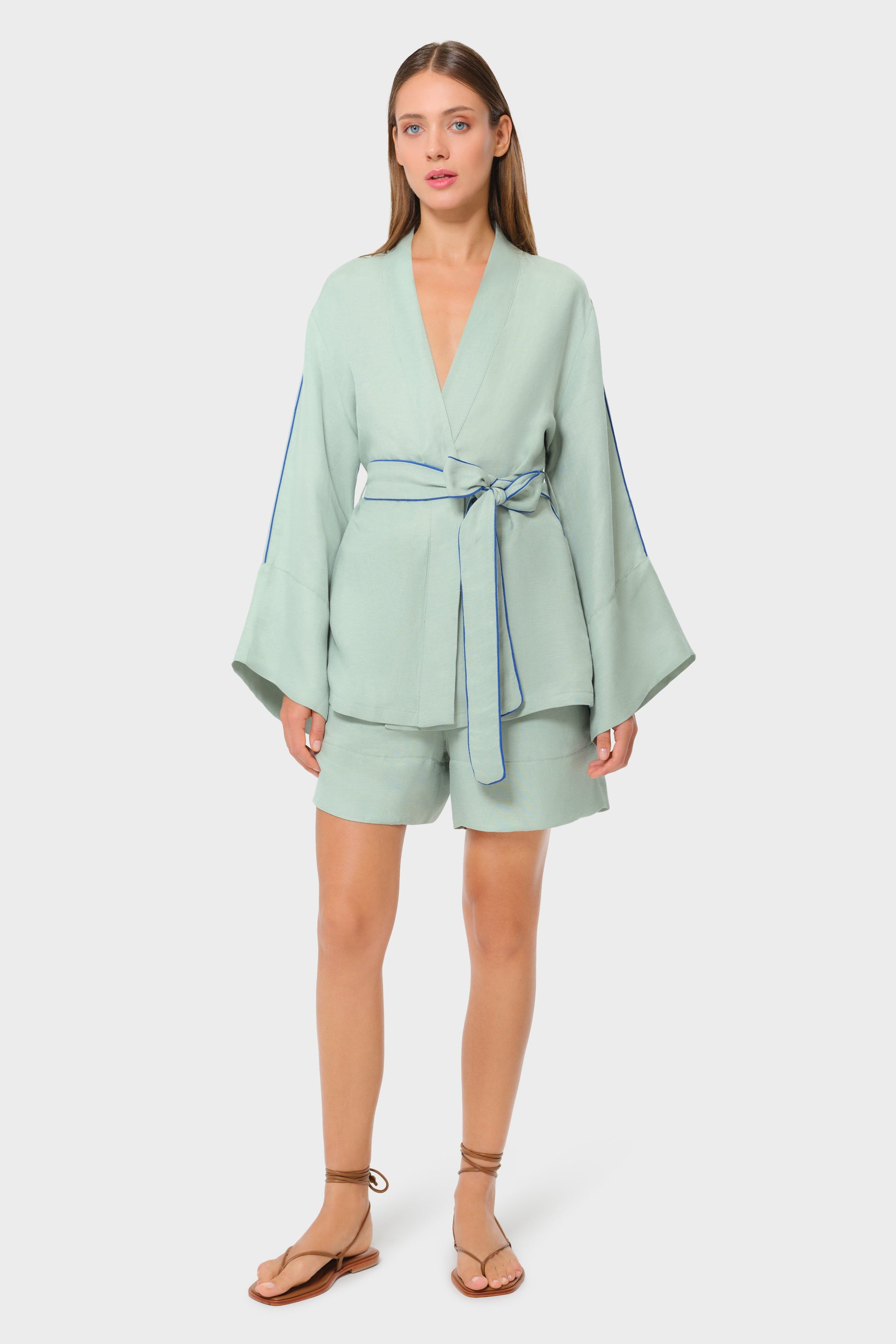 Model in sage green wrap jacket with matching lounge shorts, studio background