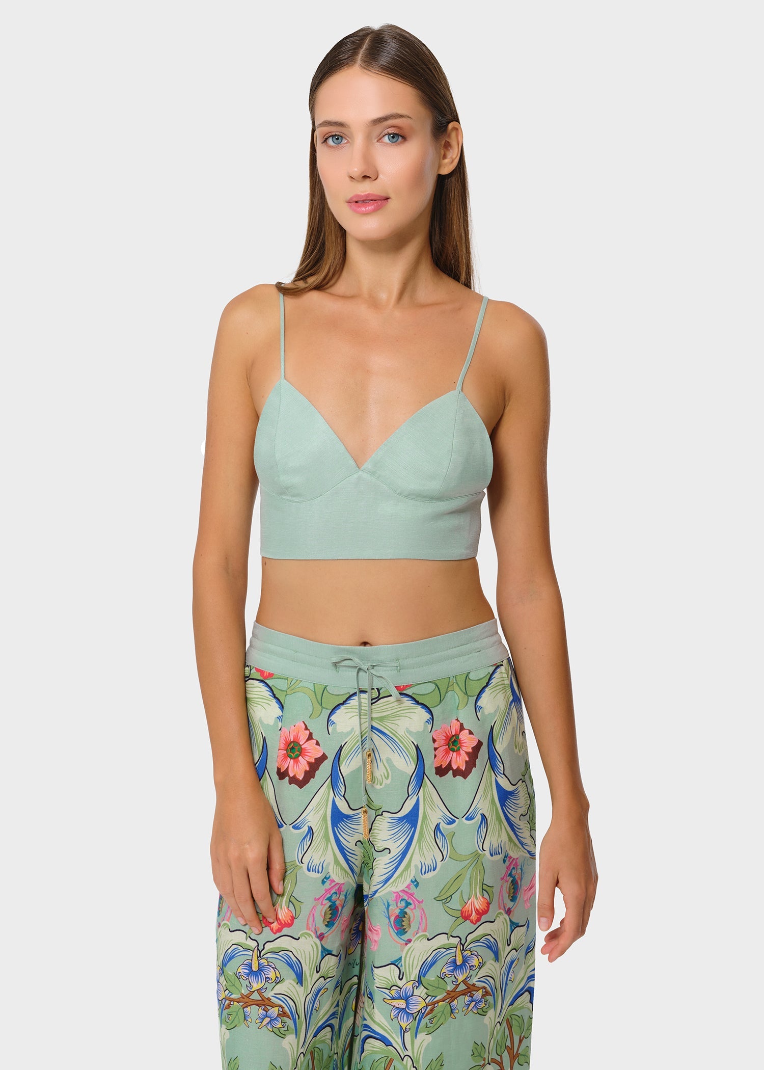 Woman wearing mint green vegan silk bralette with floral print wide leg pants, front view