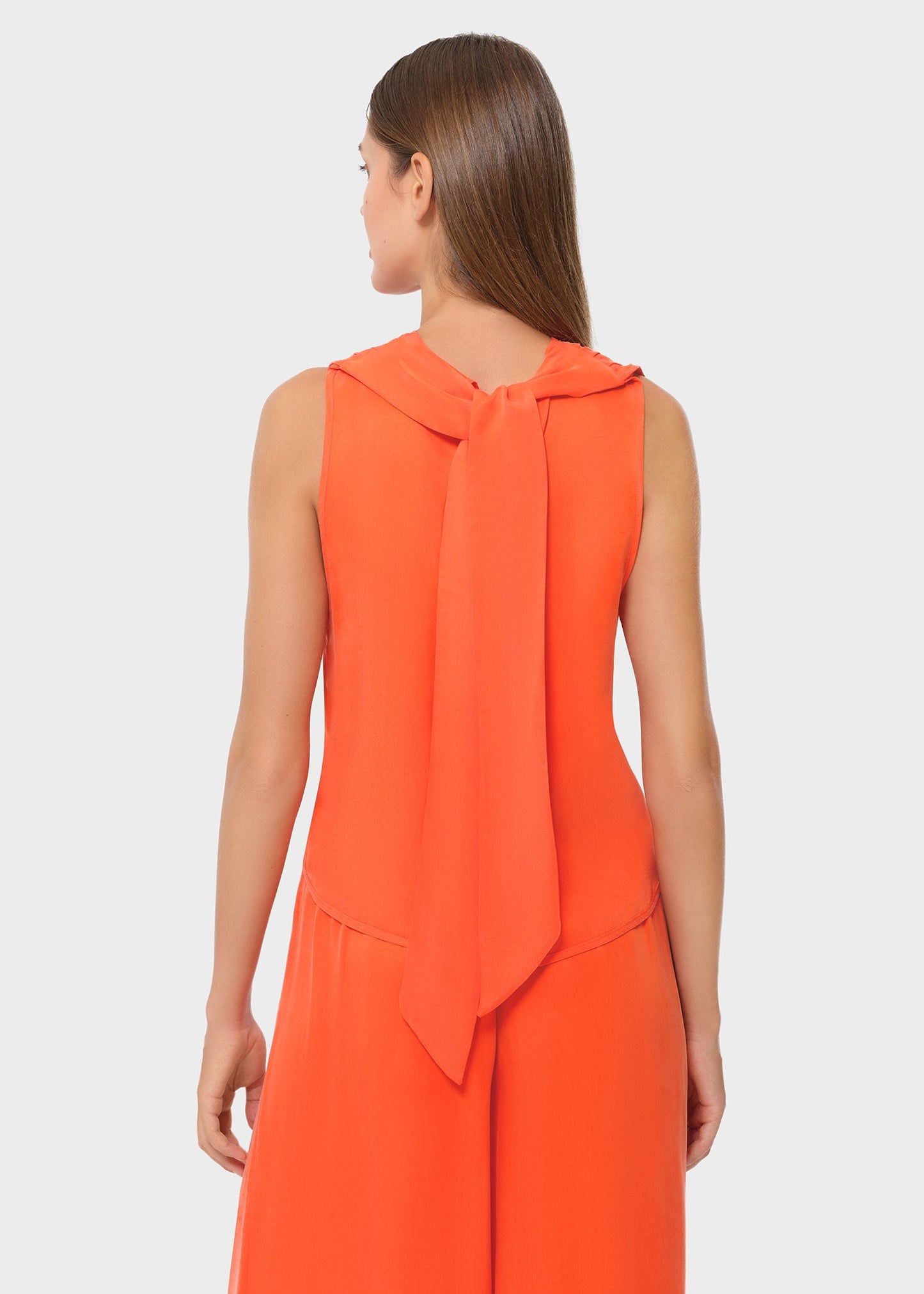 Close back view of the bright orange sleeveless top showcasing the soft tie detail at the neckline. Clean, fluid silhouette for a refined, modern look.
