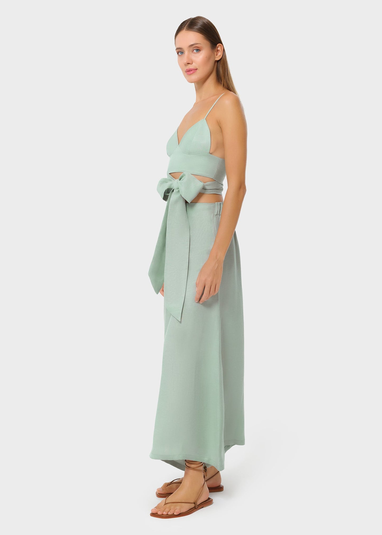 Woman wearing mint green vegan silk bralette and bow tie maxi skirt, side view