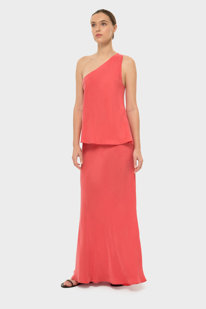 Woman in a coral one-shoulder top with a matching skirt.
