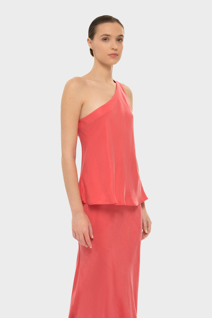 Woman in a coral one-shoulder top with a matching skirt.