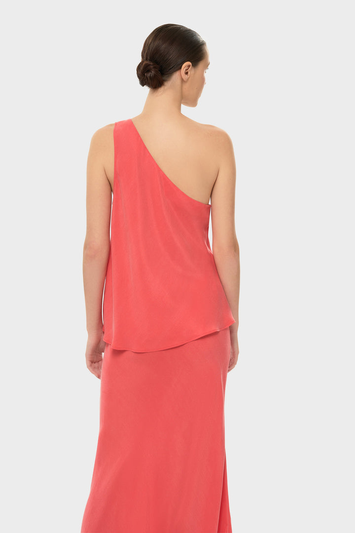 Woman in a coral one-shoulder top with a matching skirt.