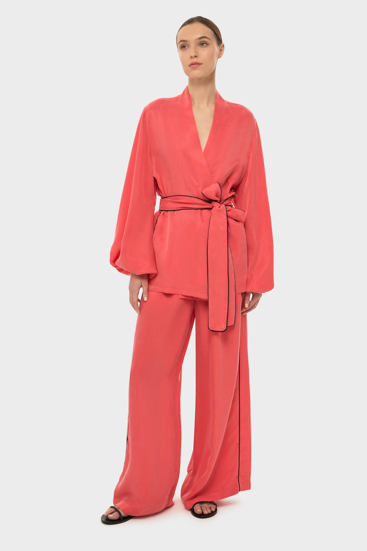 Woman in a coral wrap-style robe top with a tie belt and long sleeves.