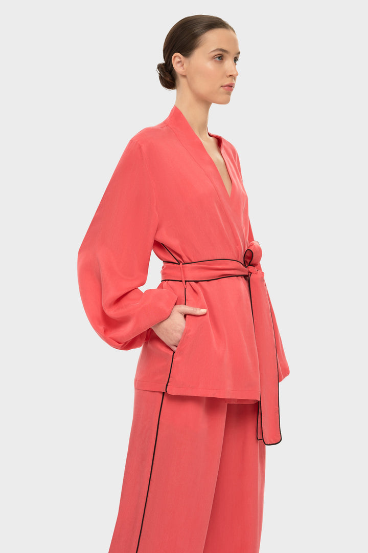 Woman in a coral wrap-style robe top with a tie belt and long sleeves.