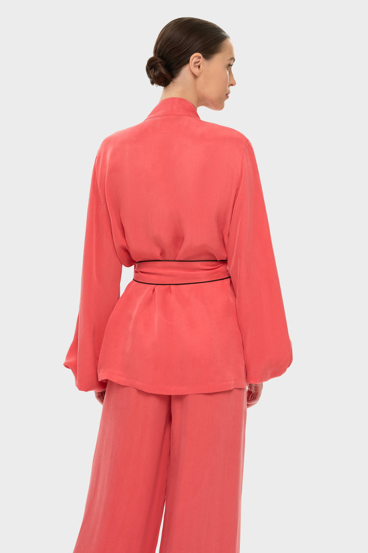 Woman in a coral wrap-style robe top with a tie belt and long sleeves.