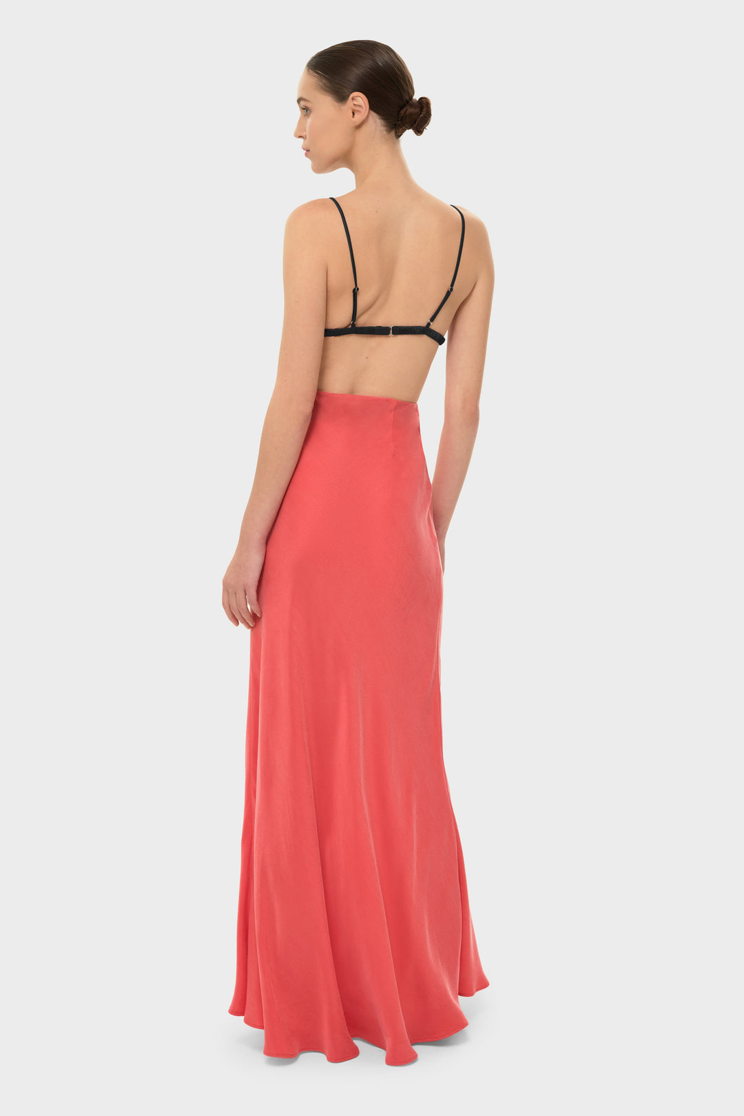 The model is wearing a black bikini top with a coral-colored maxi skirt.