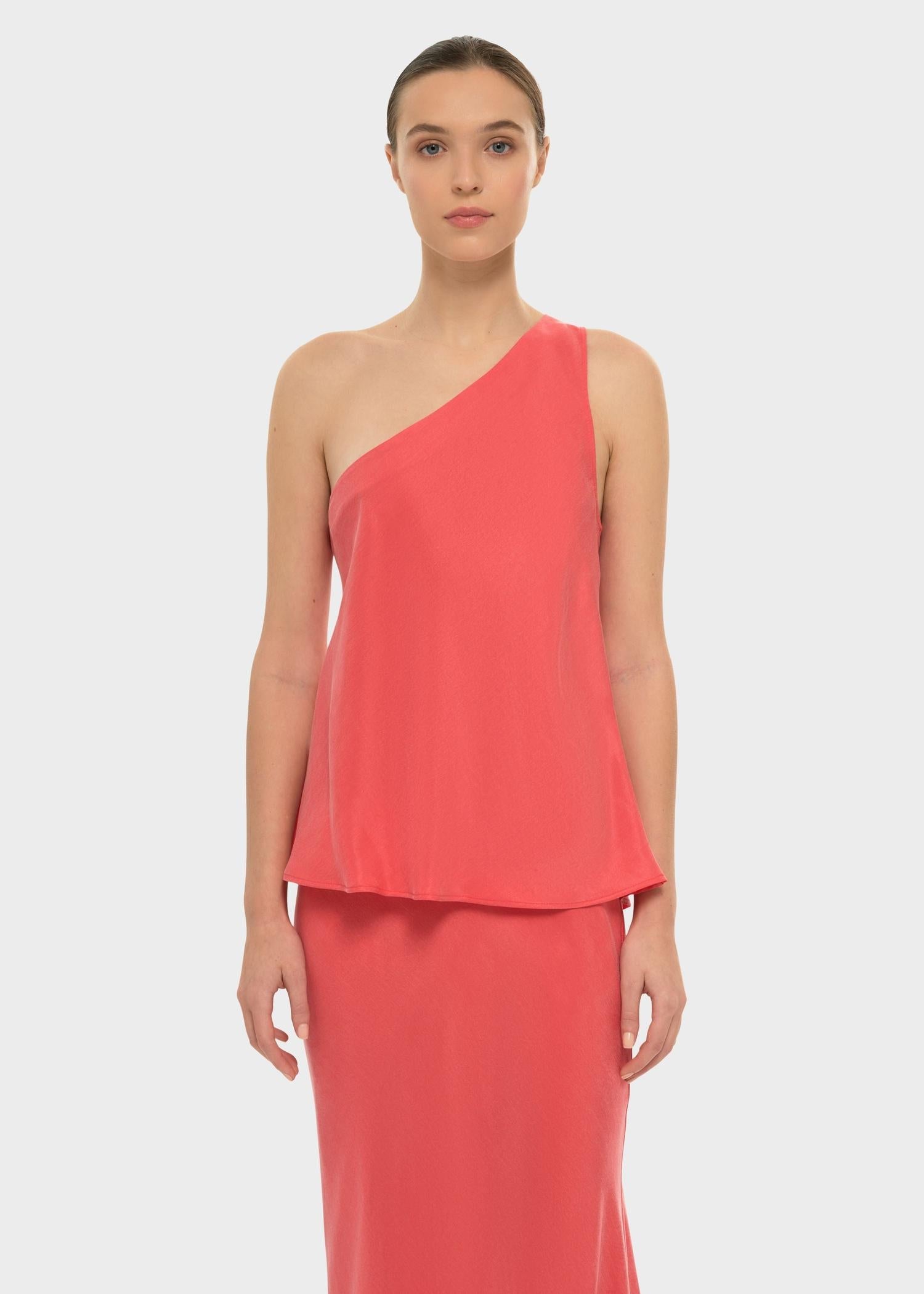 Woman in a coral one-shoulder top with a matching skirt.