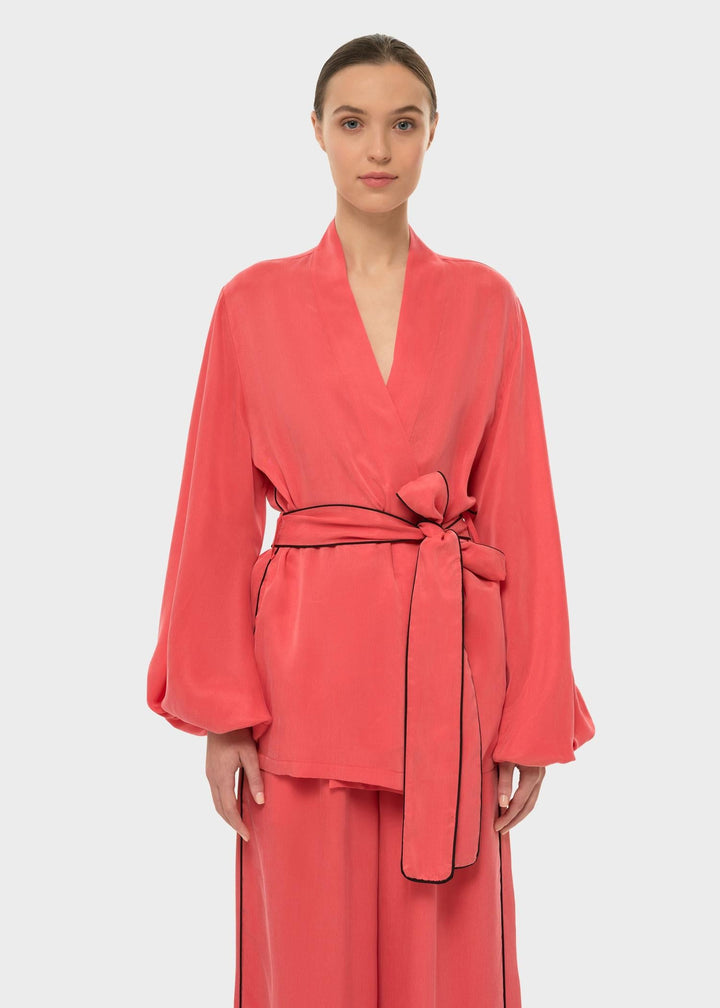 Woman in a coral wrap-style robe top with a tie belt and long sleeves.