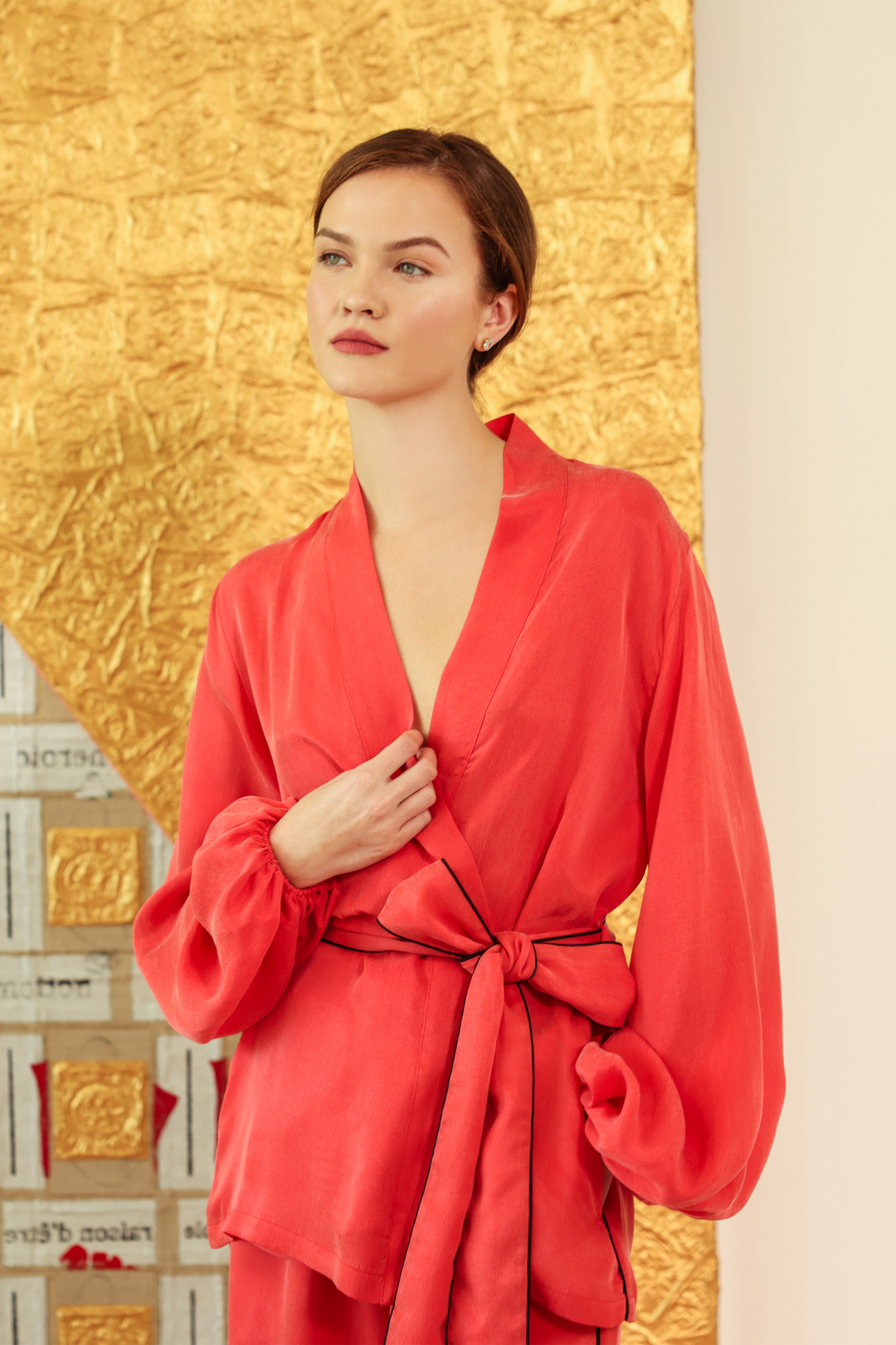 Woman in a coral wrap-style robe top with a tie belt and long sleeves.