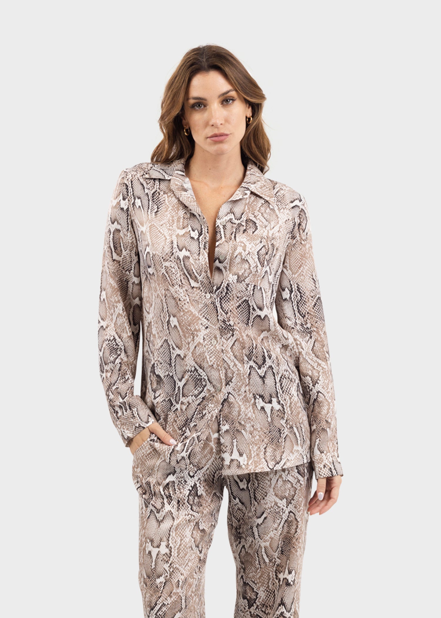 Woman wearing a gray and white snake print button-down shirt with matching snake print pants