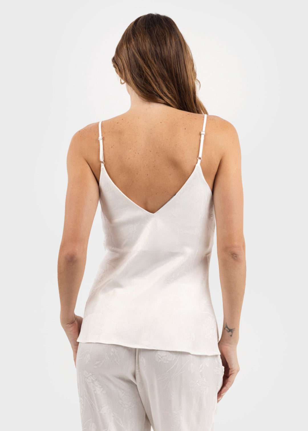 Woman wearing a white V-neck cami tank top with thin straps and a relaxed fit
