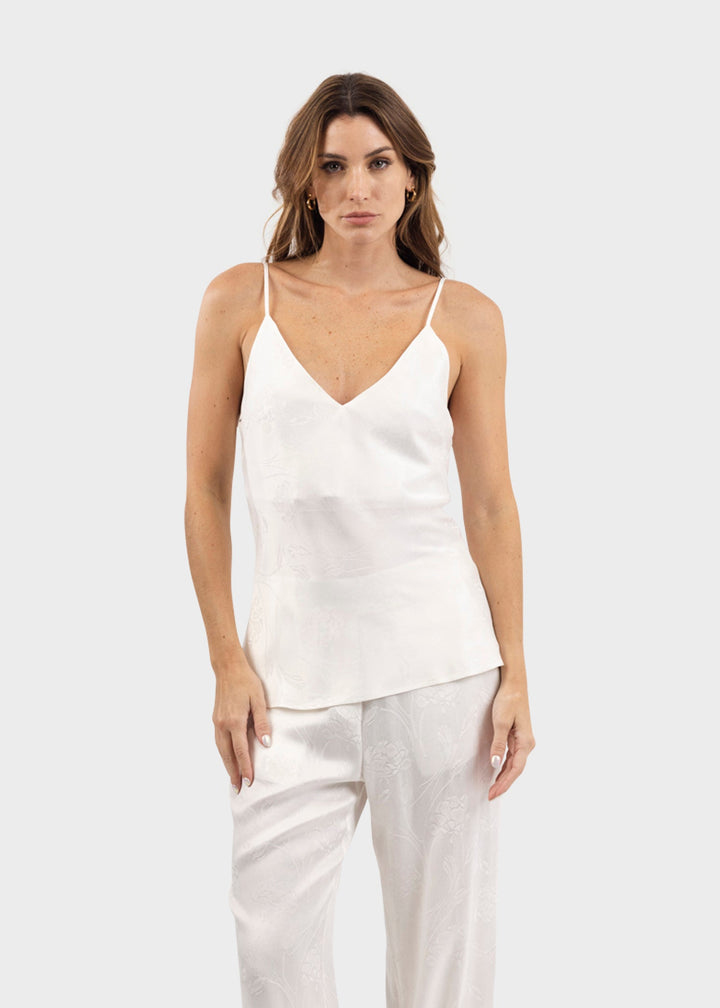 Woman wearing a white V-neck cami tank top with thin straps and a relaxed fit