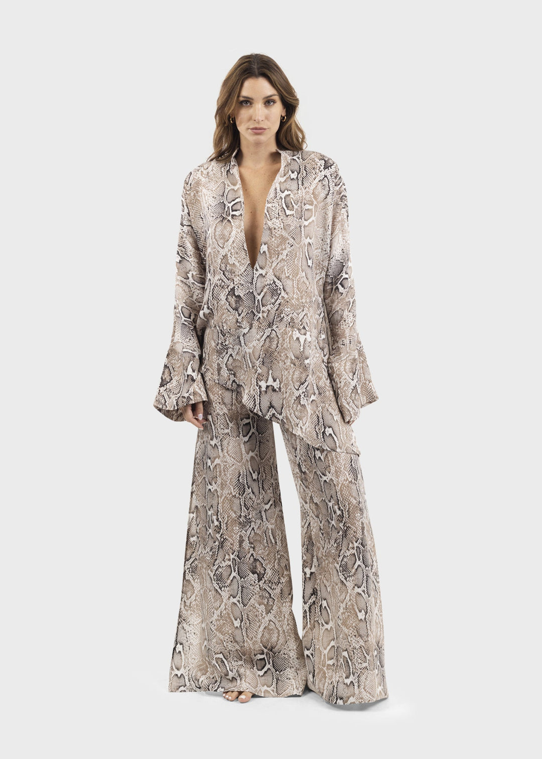 Woman wearing a gray and white snake print tunic top with long flutter sleeves and a deep V-neckline