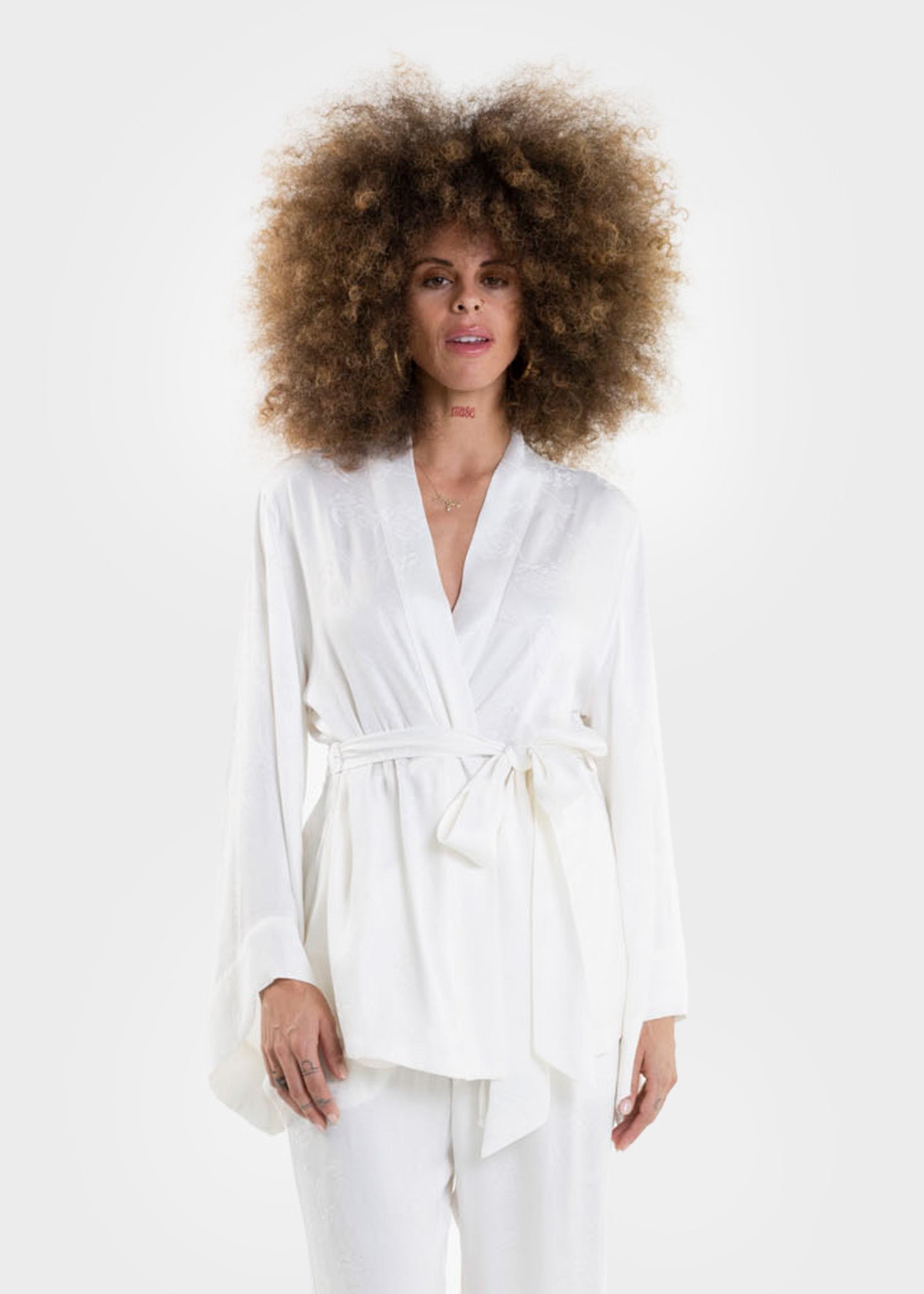 Woman wearing a white wrap top with long sleeves and a tie waist