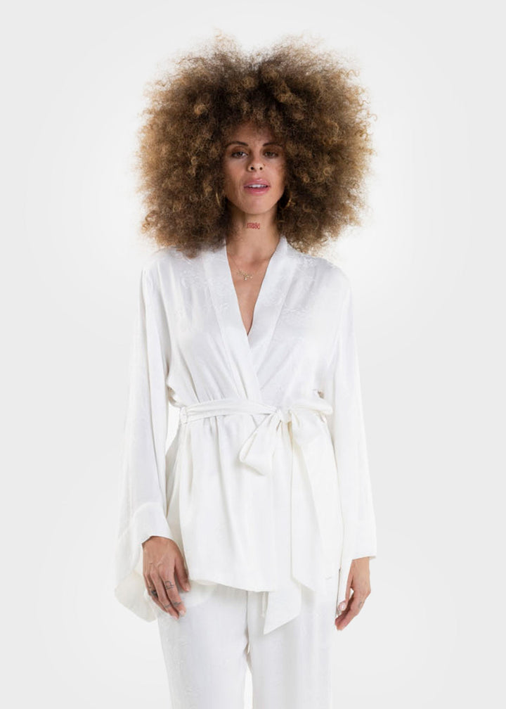 Woman wearing a white wrap top with long sleeves and a tie waist