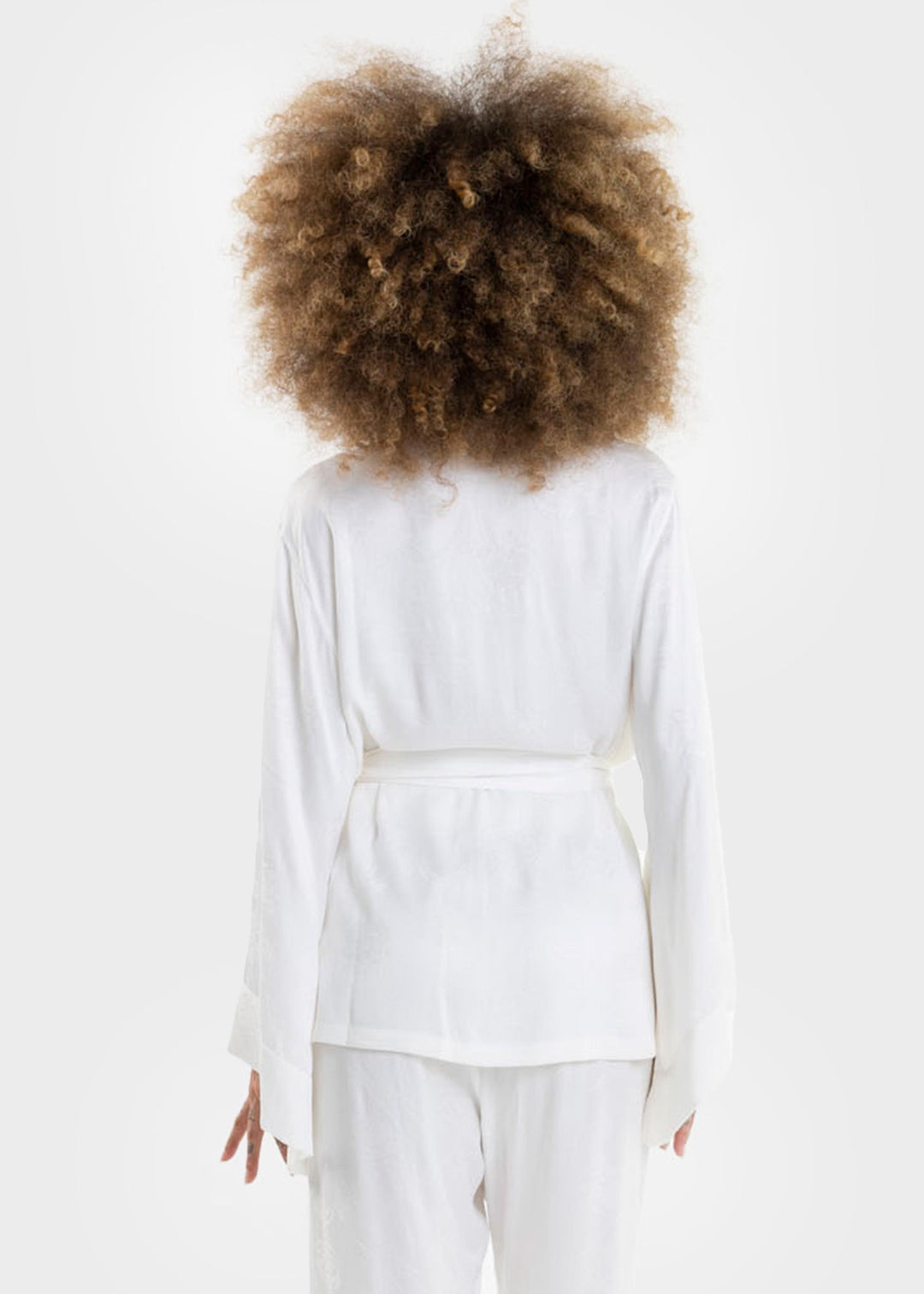 Woman wearing a white wrap top with long sleeves and a tie waist