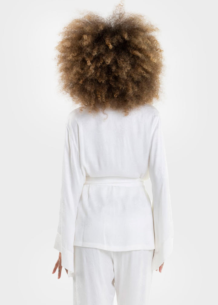 Woman wearing a white wrap top with long sleeves and a tie waist