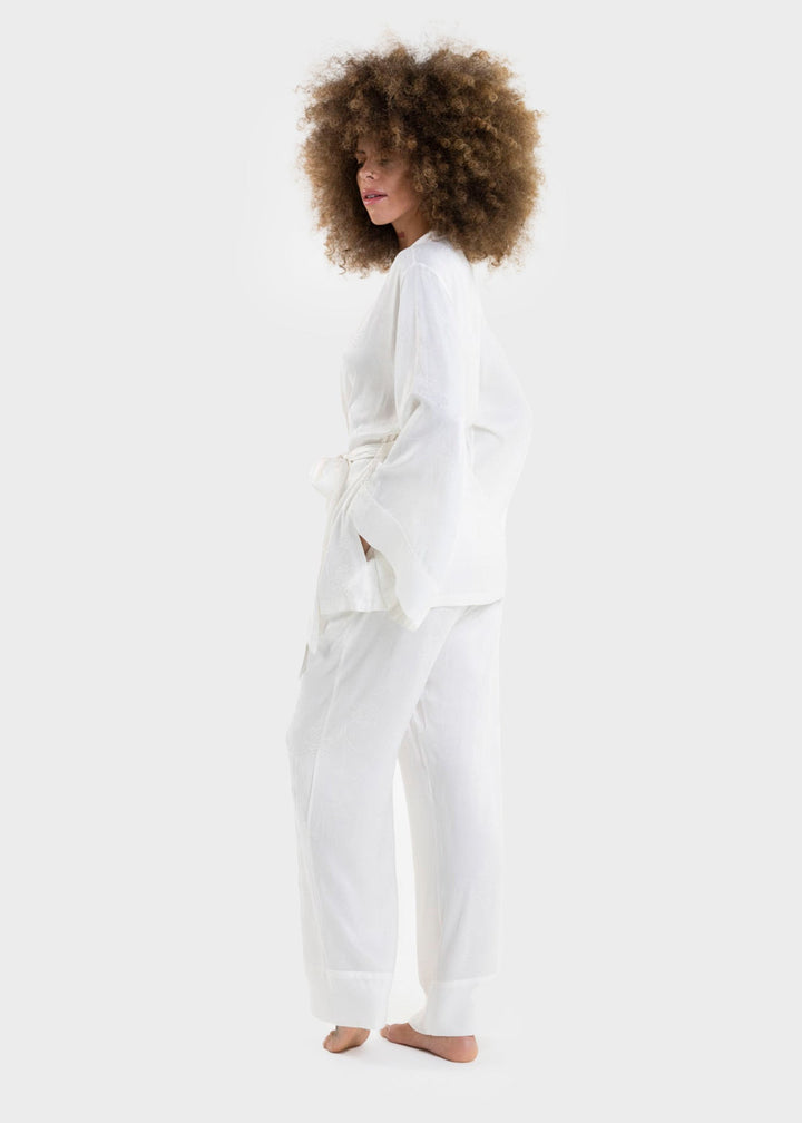 Woman wearing a white wrap top with a tie waist and matching white wide-leg pants