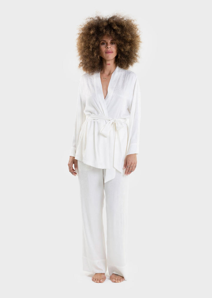 Woman wearing a white wrap top with a tie waist and matching white wide-leg pants