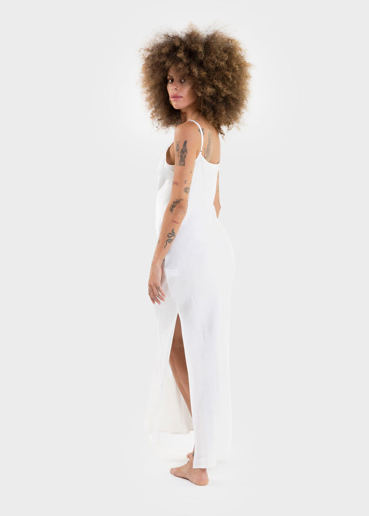 Woman wearing a white sleeveless slip dress with a V-neckline and maxi length