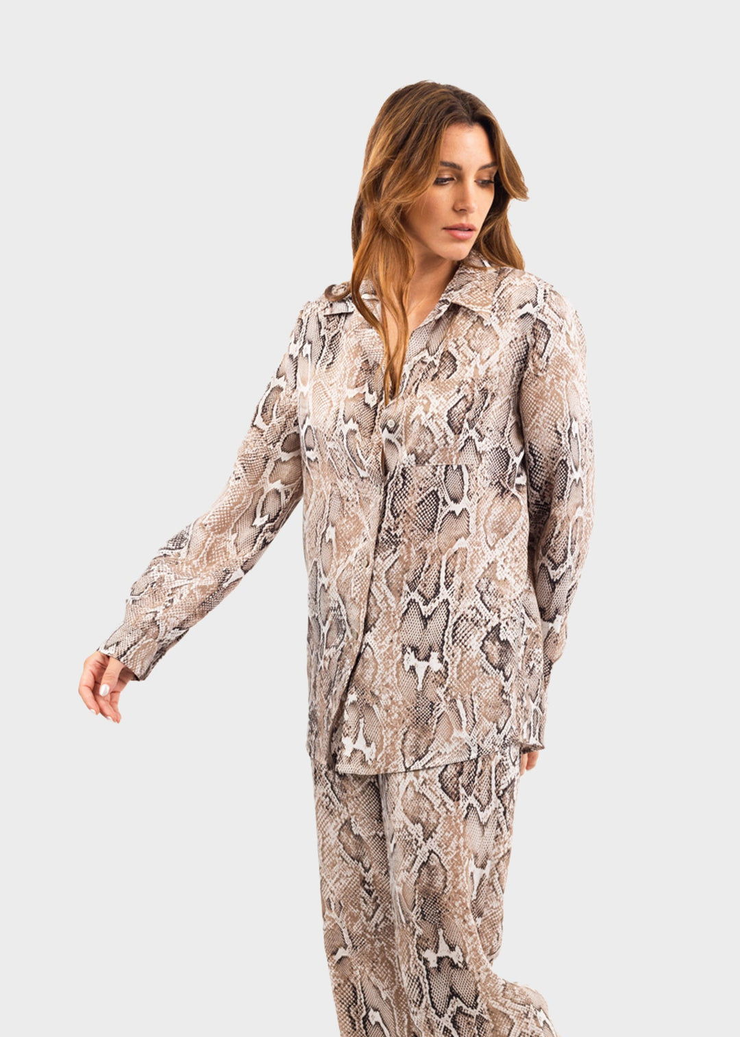Woman wearing a gray and white snake print button-down shirt with matching snake print pants