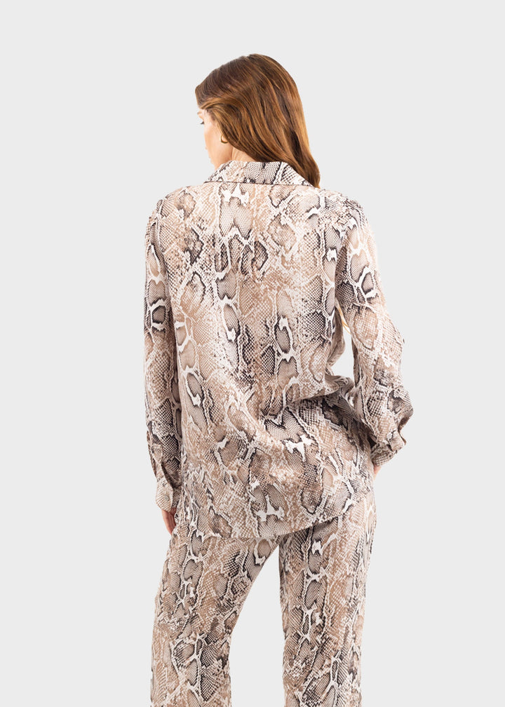 Woman wearing a gray and white snake print button-down shirt with matching snake print pants
